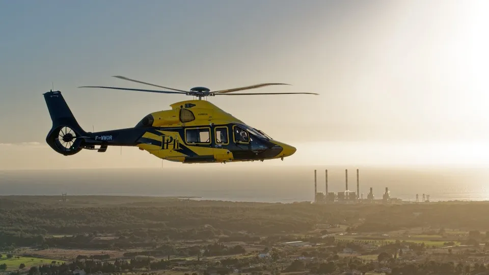 Yellow Airbus Helicopters H160 flying over rugged terrain, showcasing 3DEXPERIENCE platform-enabled design and simulation.