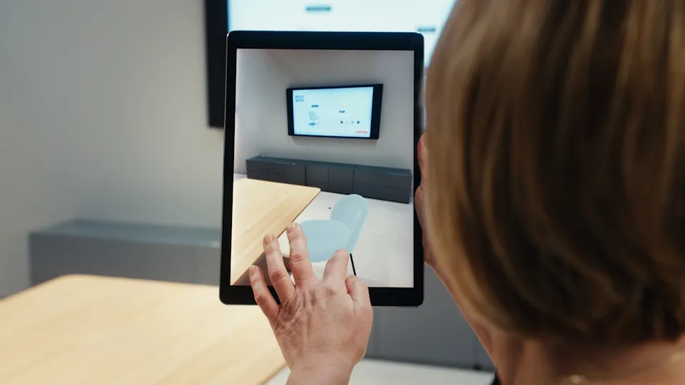Person using a tablet to visualize Rolf Benz furniture in augmented reality with the 3DEXPERIENCE platform.