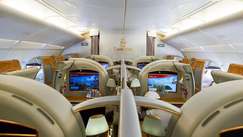 Emirates business class cabin interior with luxury seats and personal entertainment screens on an aircraft.