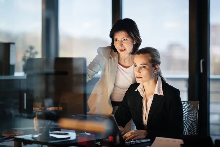Two businesswomen work on a computer in an office