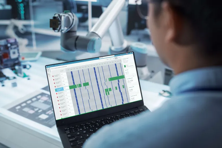 Factory worker using DELMIA MES software on tablet with Virtual Twin simulation on screen in smart manufacturing environment
