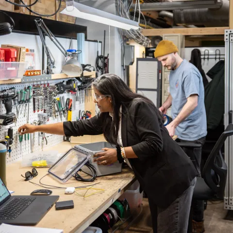 Climatetech entrepreneurs collaborating at a Greentown Labs workbench to prototype sustainable hardware solutions
